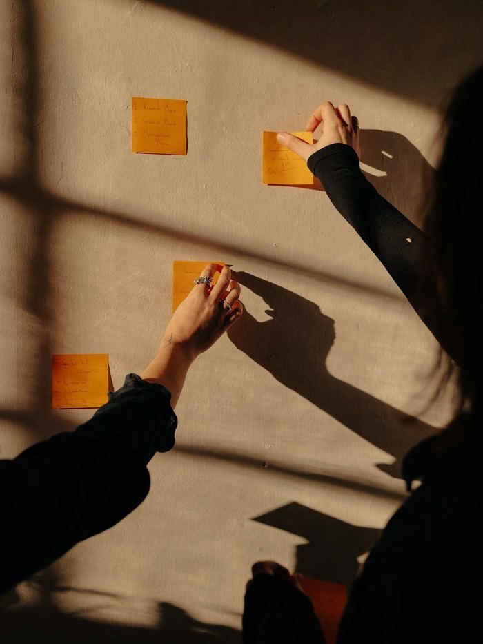 Hands pinning notes to a wall in warm light